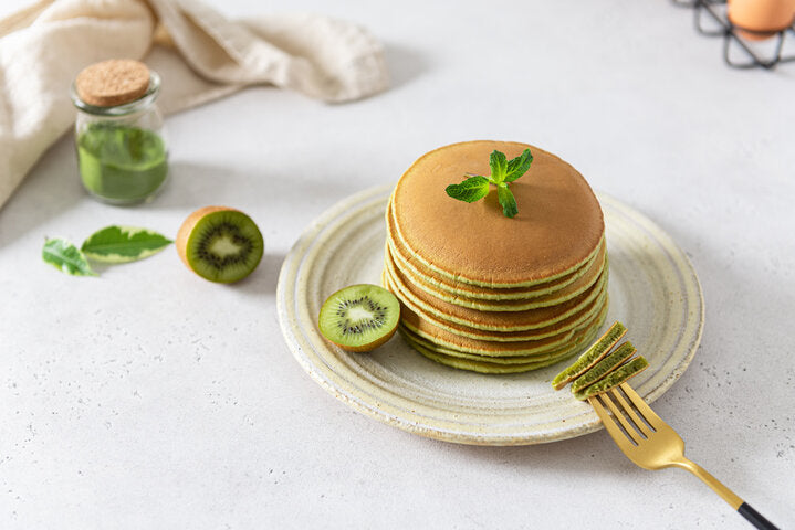 Green matcha pancakes with matcha tea or spinach. Healthy breakfast with superfoods. Light background, hugge scandinavian style. Vegan recipe, Green crepes