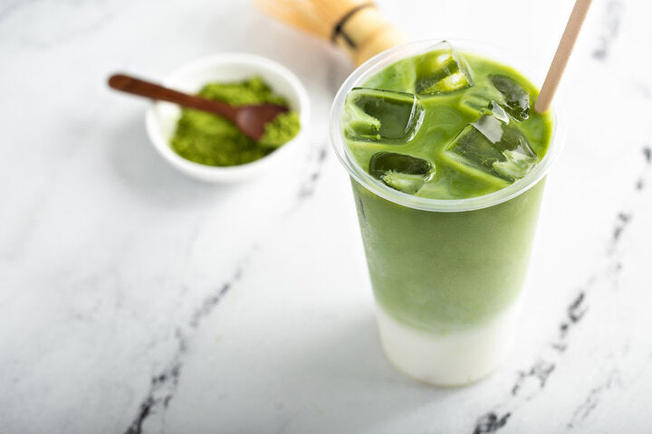 Cold matcha latte in a tall glass on marble