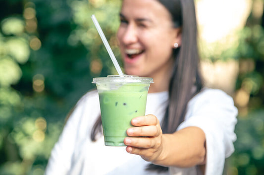 Smiling person outdoors holding iced green drink