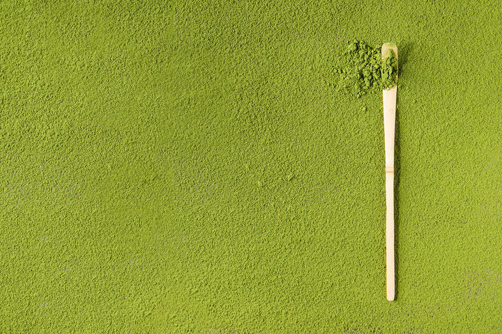 Green powder spread with bamboo scoop