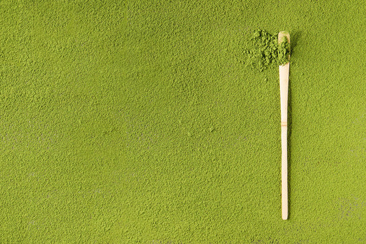 Green powder spread with bamboo scoop