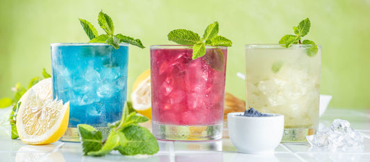 Three iced colorful drinks with mint, lemon, ice