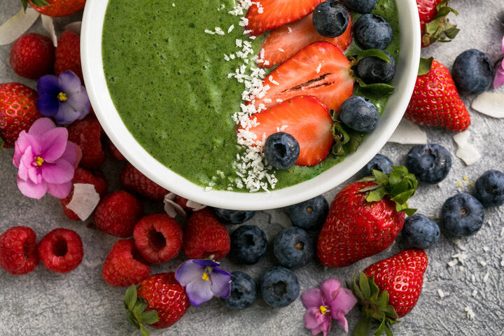 Overhead green smoothie bowl with strawberries, blueberries, coconut