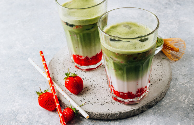Pink and green layered strawberry matcha latte in clear glass
