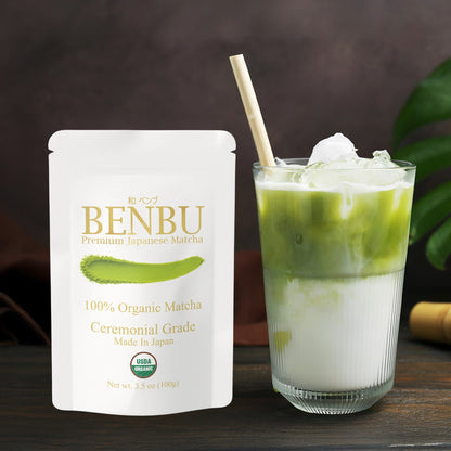 BENBU Organic ceremonial grade matcha 100 g bag next to iced matcha latte on wooden surface