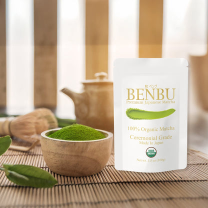BENBU Organic Matcha 100 g bag with bowl of matcha powder and tea tools on wooden surface